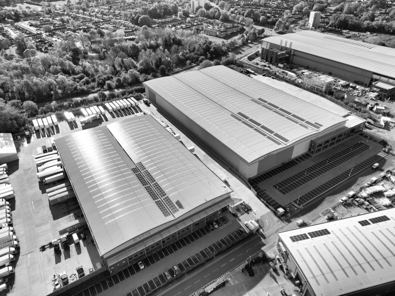 Aerial monochrome image of industrial warehouses and parking spaces in Hertfordshire, UK.