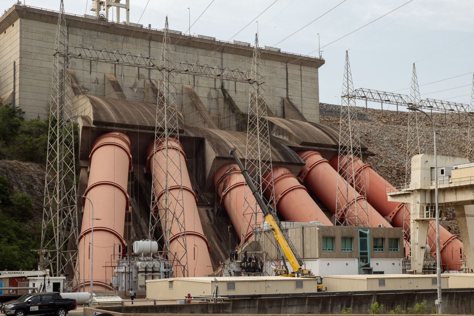 Complex view of a hydroelectric dam with large turbines and power lines demonstrating energy infrastructure.
