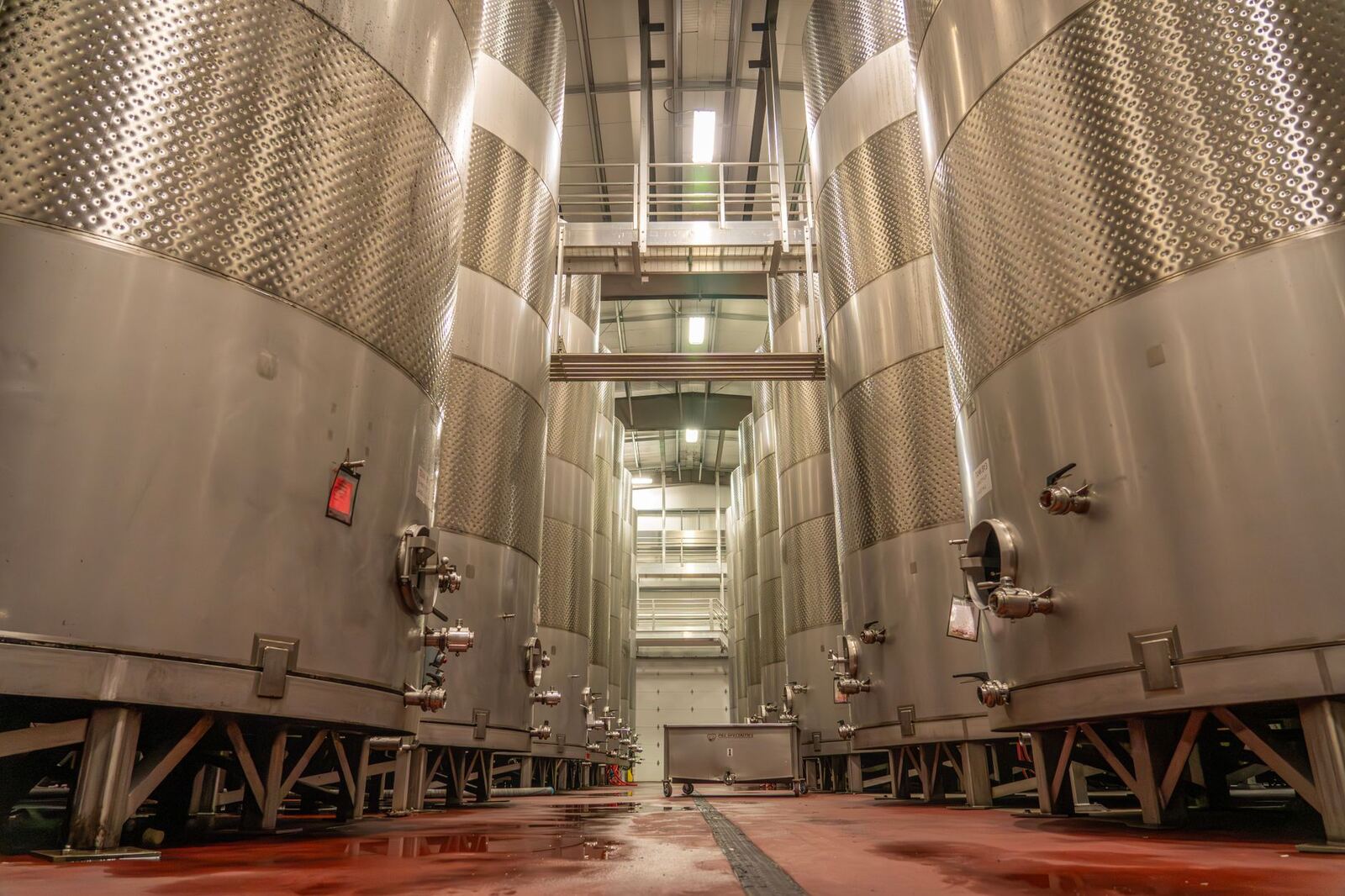 Interior of an industrial brewery with large, stainless steel fermentation tanks.