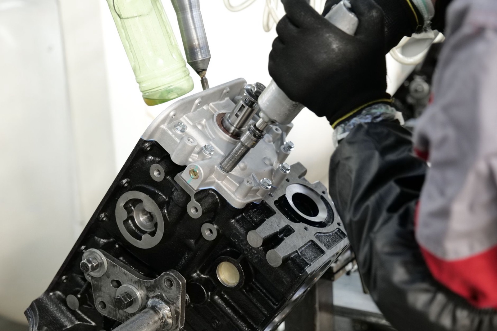 Skilled mechanic working on engine assembly with precision tools in factory setting.