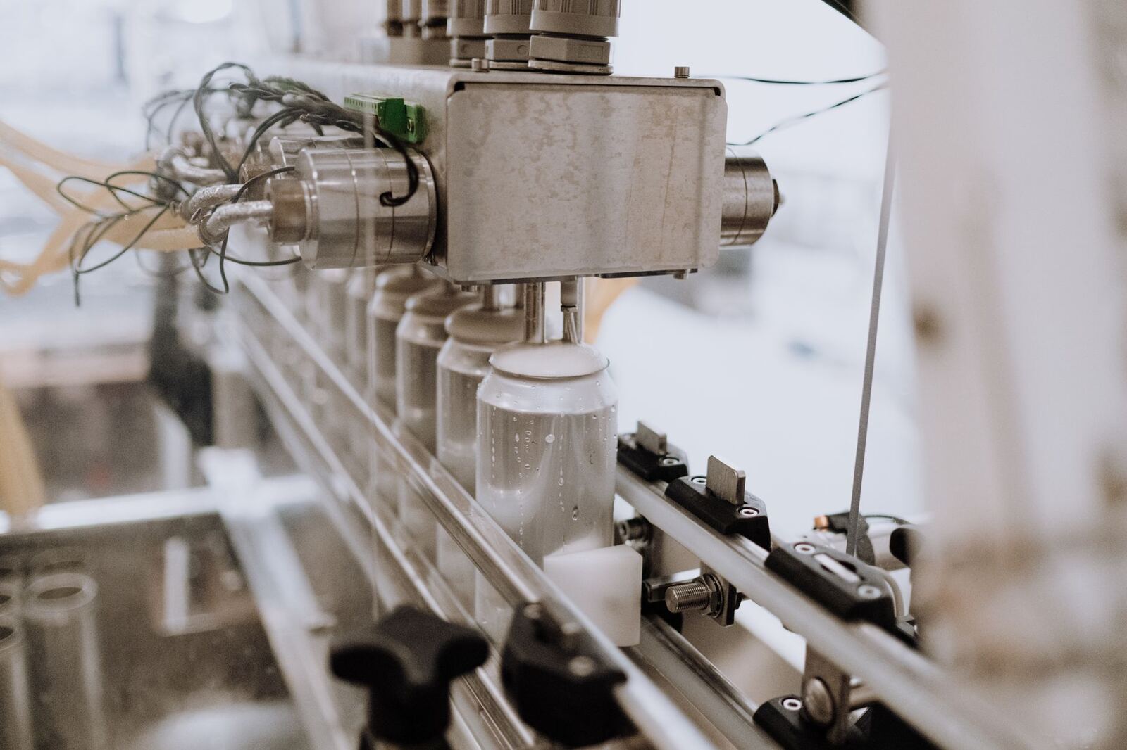 Close-up of an automated can filling machine in a beverage production line.